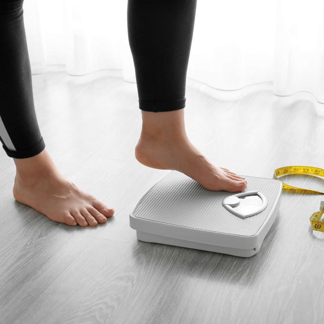 A person stepping on to a scale worried about weight loss symptons