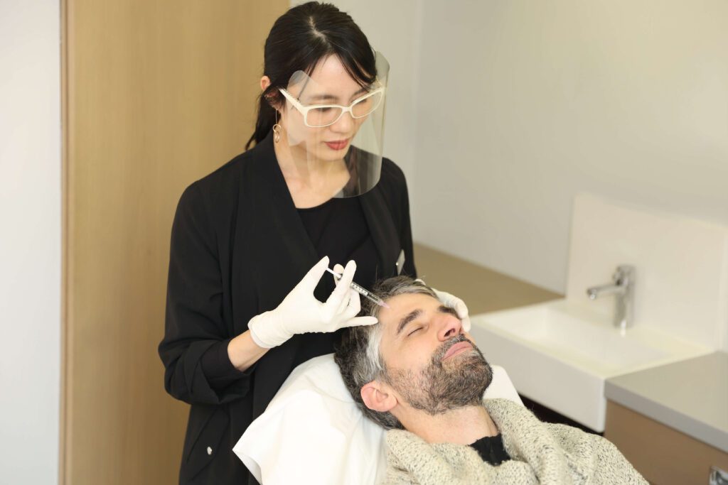 dr thu linh performing forehead botox on a male patient